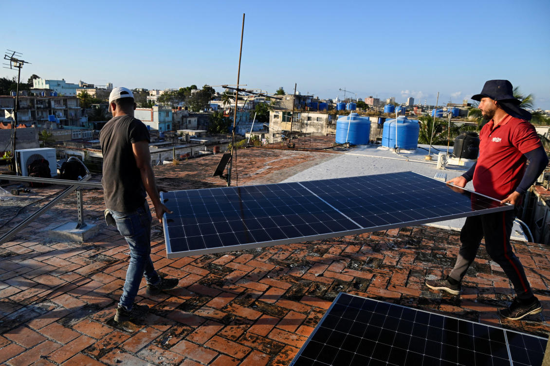 Solar panel technicians Denis Tamayo, 30, and Alejandro Guerra, 30, carry a solar panel on the rooftop of a building as Cubans grapple with an ongoing energy crisis exacerbated by fuel shortages, Havana, Cuba February 16, 2026. REUTERS/Norlys Perez