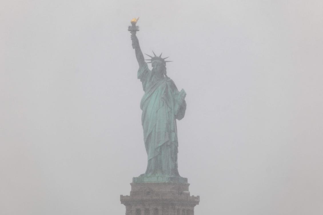 The Statue of Liberty is partly obscured as snow begins to fall as the city braces for a blizzard on Sunday on February 22, 2026, in New York City. (Getty Images via AFP)