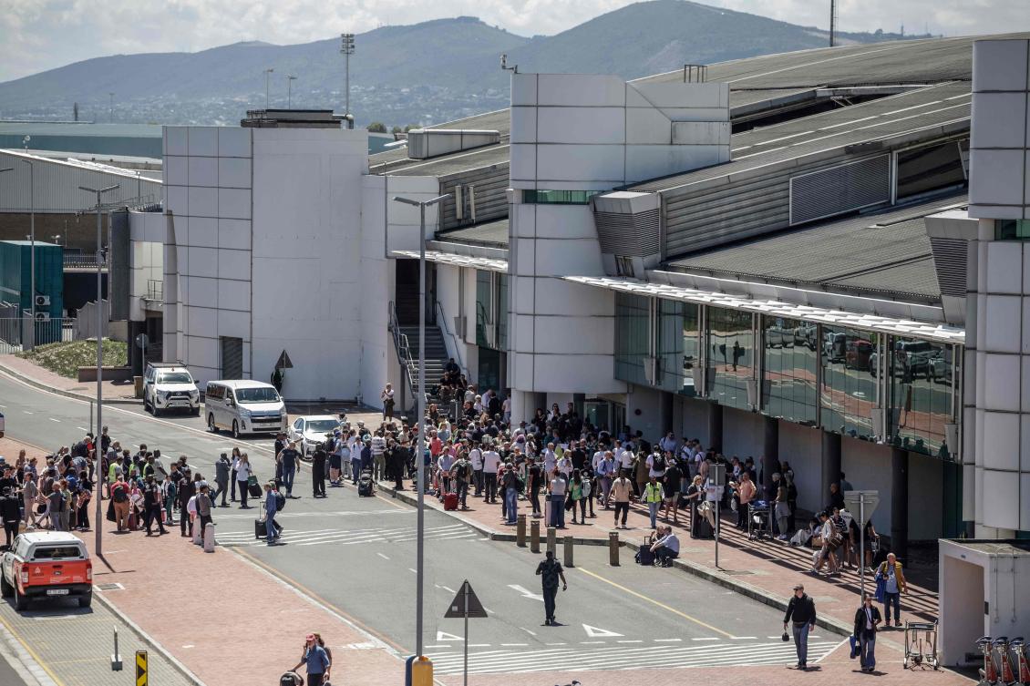 Passengers are seen stranded outside one of the terminals of the Cape Town International Airport on February 24, 2026 following reports of a fire that broke out earlier today. (AFP)