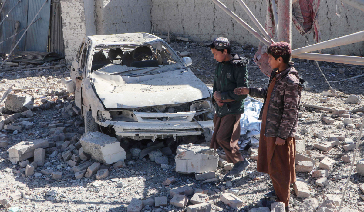 Afghan children walk past a damaged car after an overnight Pakistani airstrike at the Balish village in Urgun district, Paktika Province, on February 22, 2026. (AFP)
