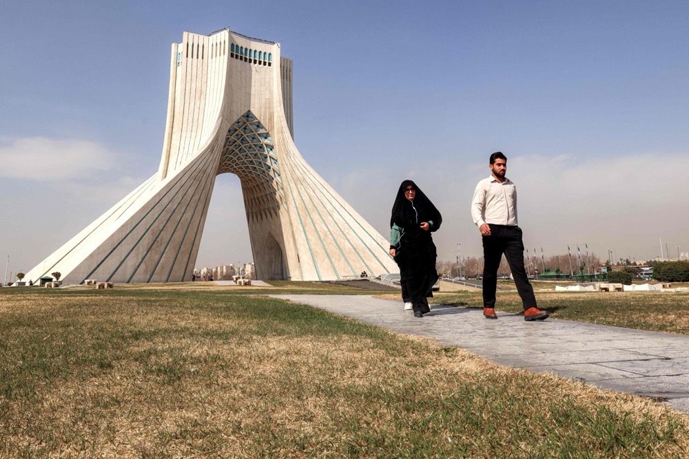 A man and woman walk at Azadi (Freedom) Square near Tehran's landmark Azadi Tower on February 23, 2026. (AFP)