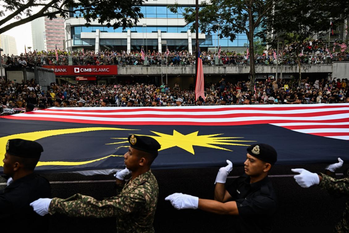 Above, armed forces personnel carry a national flag during Malaysia’s National Day celebration parade in Kuala Lumpur on Aug. 31, 2022. (AFP file photo)