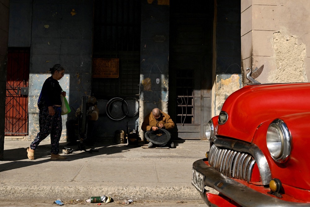 A man repairs a bicycle tire on the sidewalk, as Cuba grapples with fuel shortages after the US blocked oil shipments to the island, in Havana, Cuba. (Reuters)