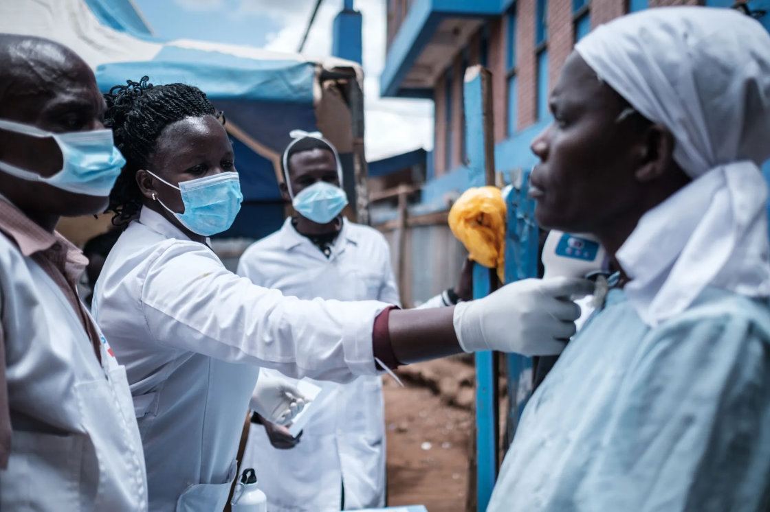 An aid worker measures a woman's temperature at the Kibera slum in Nairobi, Kenya. (AFP/File)