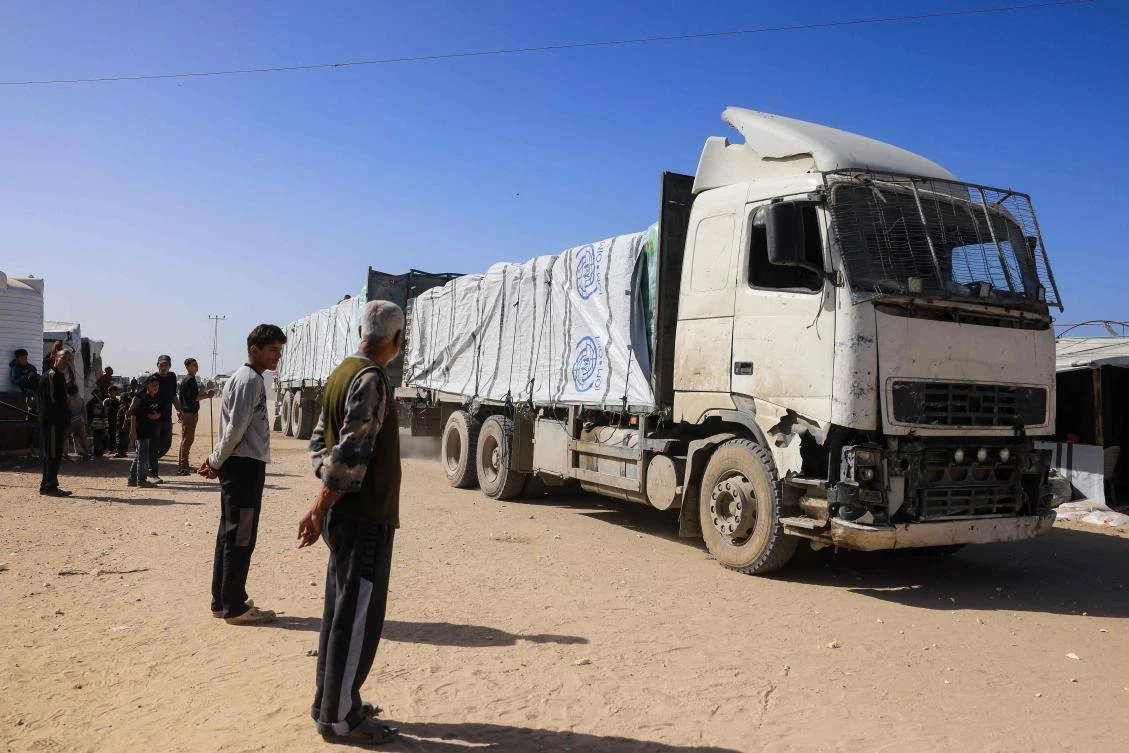 Palestinians look on as trucks carrying humanitarian aid arrive in Khan Yunis in the southern Gaza Strip, after passing through the Rafah border crossing from Egypt, on February 1, 2026. (AFP)