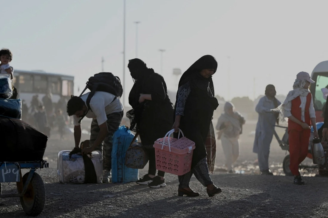 Afghan refugees carrying their belongings as they arrive at the zero point of the Islam Qala border crossing between Afghanistan and Iran. (AFP)