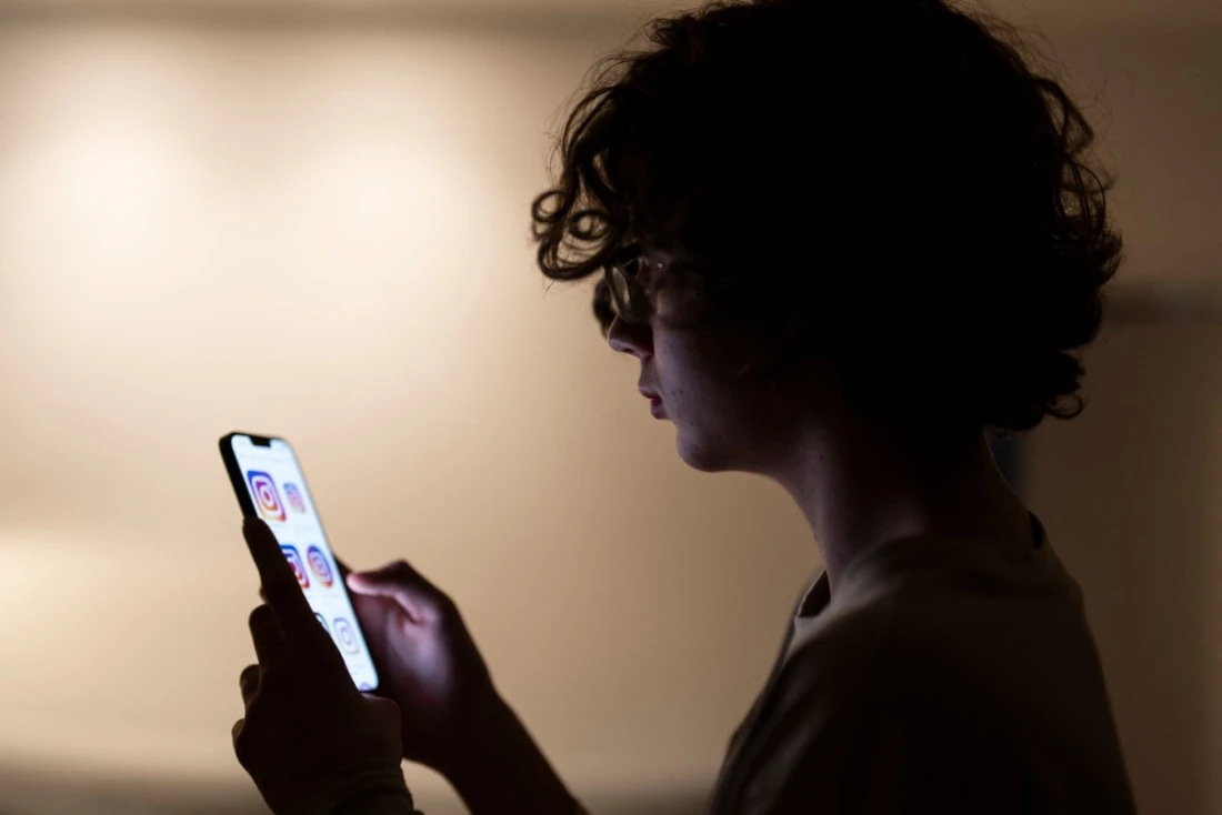 A teenager scrolling through social media apps on his phone. (AFP)