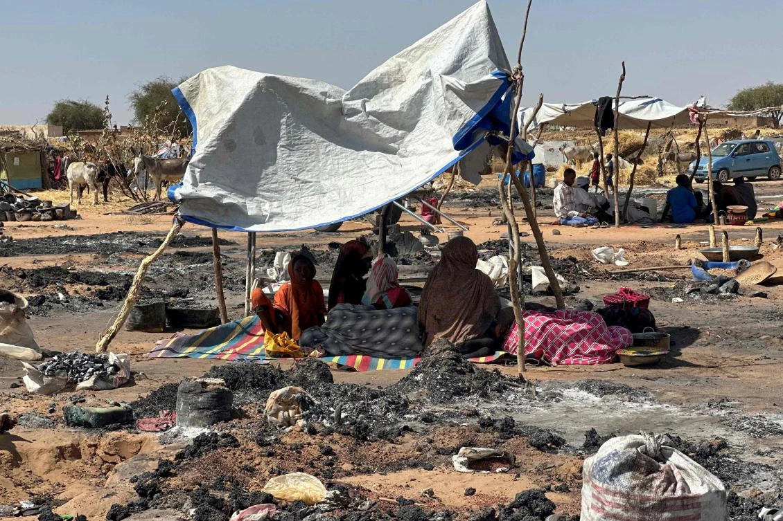 Refugees displaced from El-Fasher after its fall to the RSF sit in the shade in Tawila camp. (AFP)