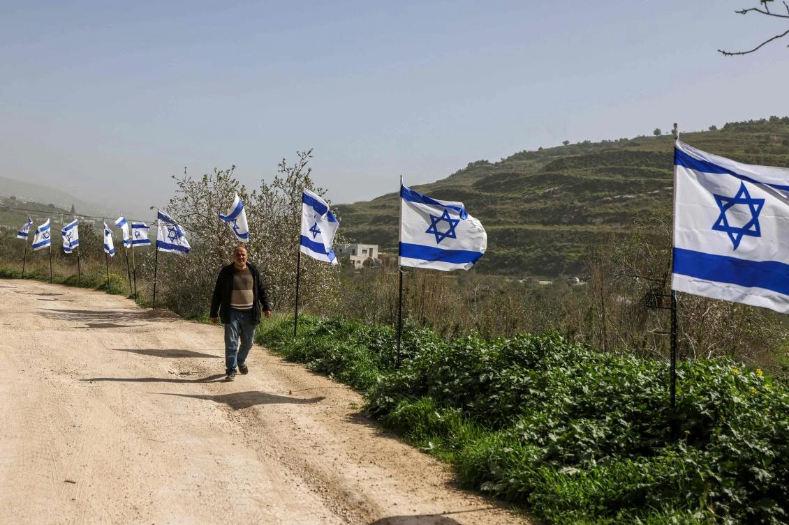 Palestinian man walks past a fence decorated with Israeli flags installed by Jewish settlers in the northern Israeli-occupied West Bank on February 15, 2026. (AFP)