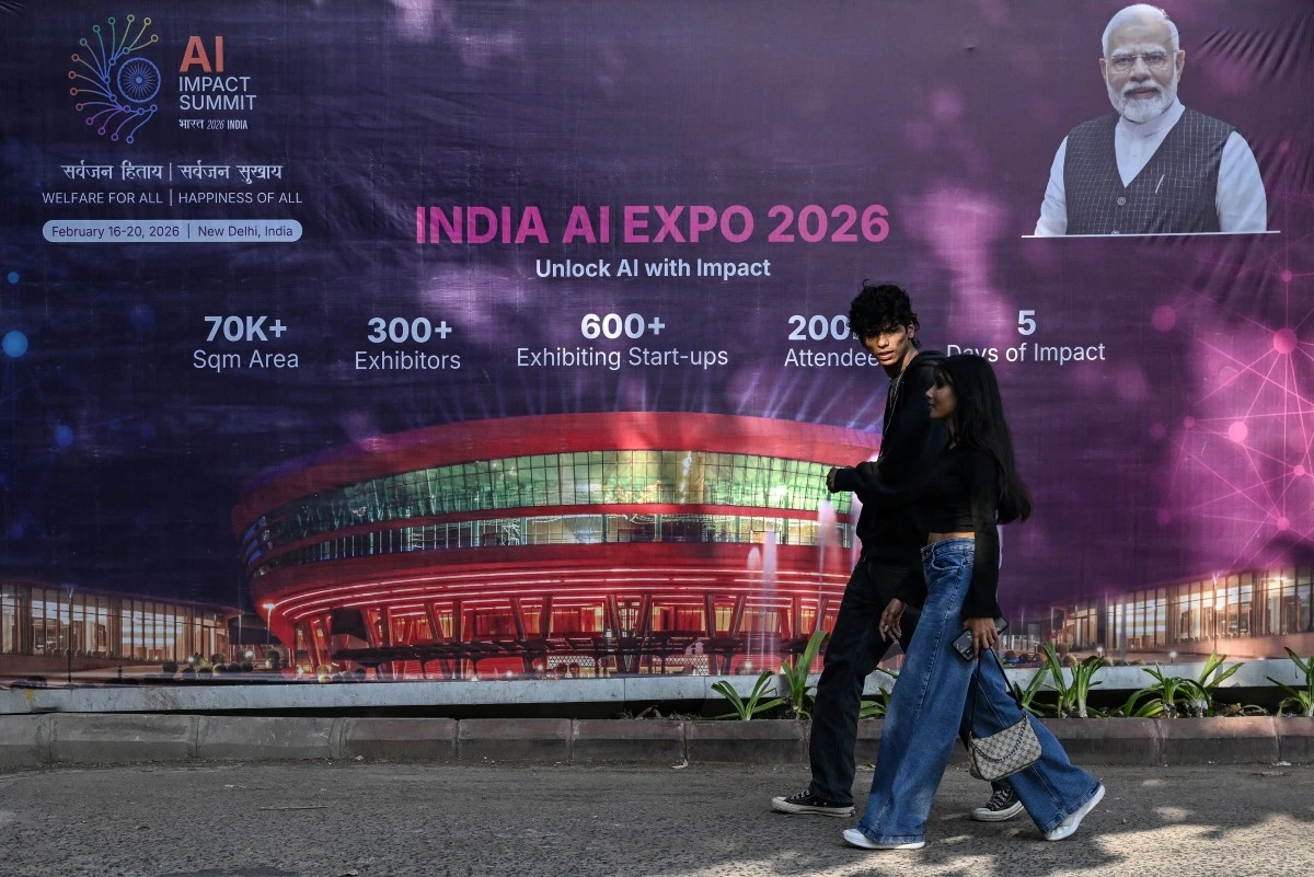 Commuters walk past a hoarding of the AI Expo along a street on the eve of the India AI Impact Summit 2026 in New Delhi on Feb. 15, 2026. (AFP)