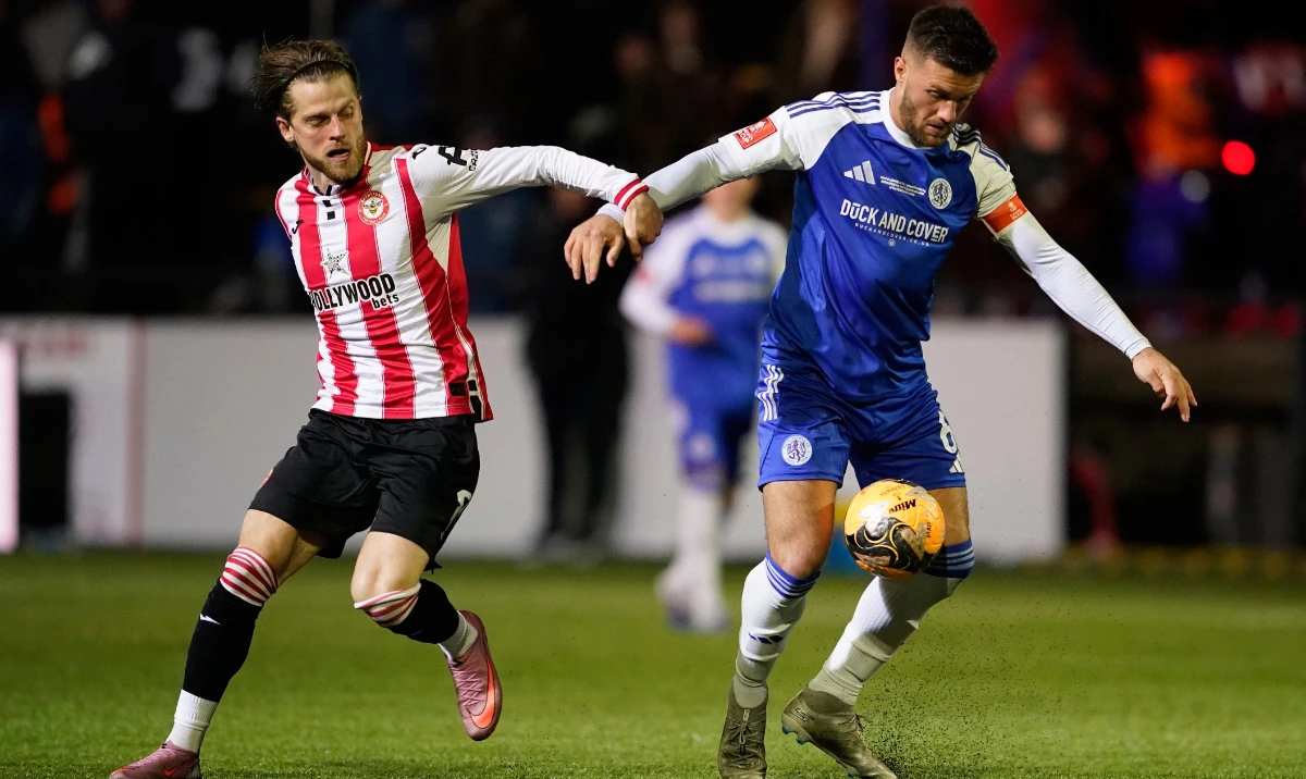 Brentford's Mathias Jensen, left, and Macclesfield's Paul Dawson fight for the ball during the English FA cup fourth round soccer match between Macclesfield and Brentford in Macclesfield, England, Monday, Feb. 16, 2026. (AP)