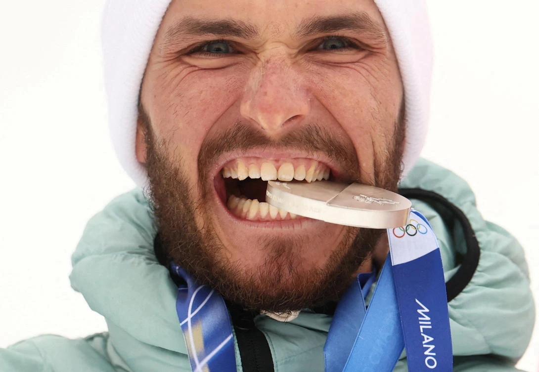 Silver medallist Nikita Filippov of AIN (Individual Neutral Athletes) bites his medal as he celebrates during the Ski Mountaineering — Men’s Sprint Victory Ceremony Milano Cortina 2026 Olympics — Stelvio Ski Center, Bormio, Italy — Feb. 19, 2026. (Reuters)