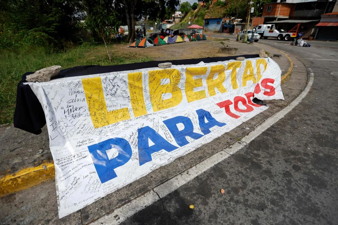 Above, a banner reading “Freedom for all” is displayed in front of El Rodeo I prison in Guatire, Miranda state, Venezuela on Feb. 20, 2026. (AFP)