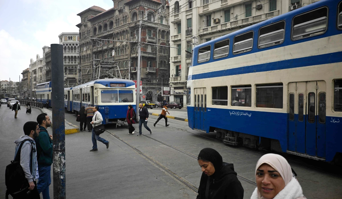 People walk past trams, one of the oldest means of transport which is earmarked fro renovation, in the coastal city of Alexandria, on February 18, 2026. (AFP)