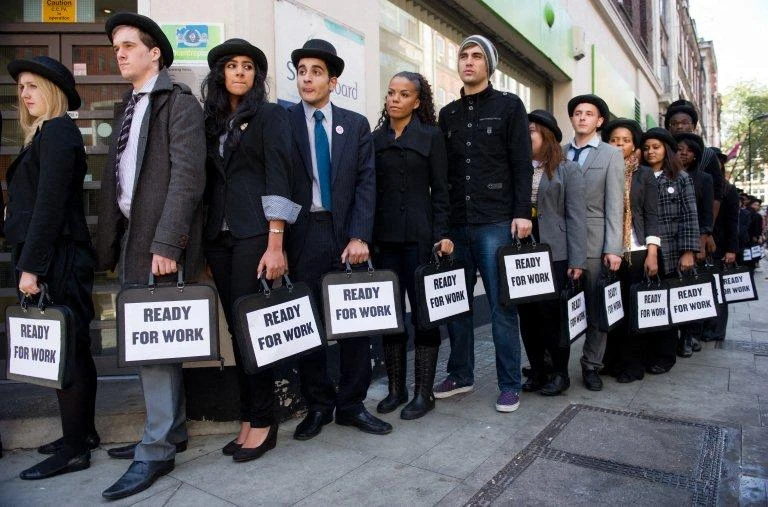 British musicians Miss Dynamite, fifth left, and Charlie Simpson, sixth left, join unemployed young people as they stand in line outside a job center in central London on Oct.10, 2011 during a photocall for the Battlefront Campaign. (AFP file photo)