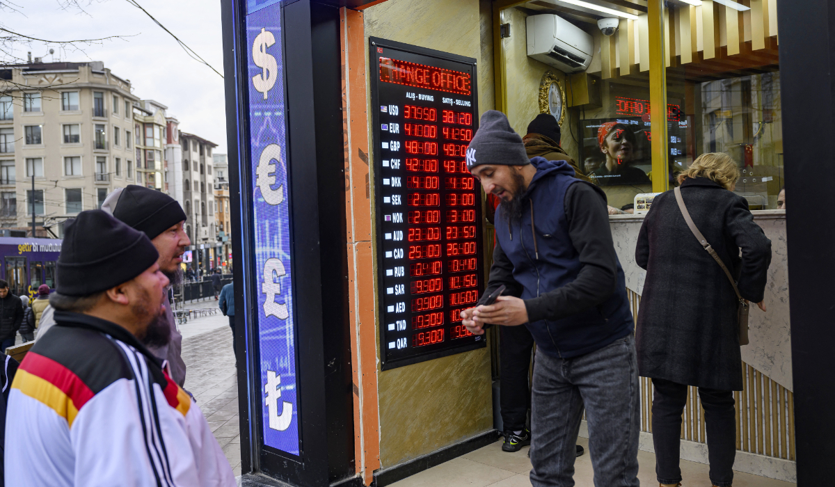 People stand next to a currency exchange board showing the Turkish Lira which fell to historic lows against the dollar, a day after the arrest of Istanbul's Mayor Ekrem Imamoglu in Istanbul, Turkey on March 20, 2025. (AFP)