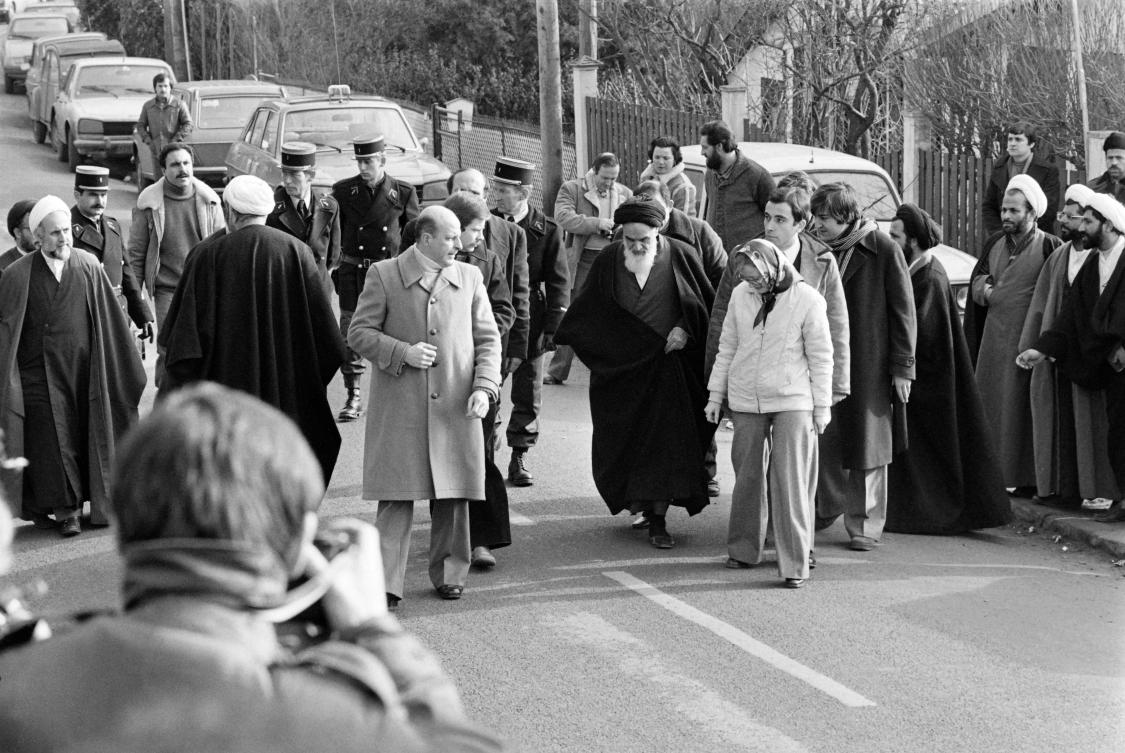 Future Iranian President Hassan Rohani (background 2nd-R, with turban and glasses) is seen among companions of opposition leader in exile ayatollah Ruhollah Khomeiny (C-white beard) walking out of his villa in Neauphle-Le-Château near Paris on January 31, 1979 before boarding an Air France "Jumbo Jet" bound to Tehran. (AFP)
