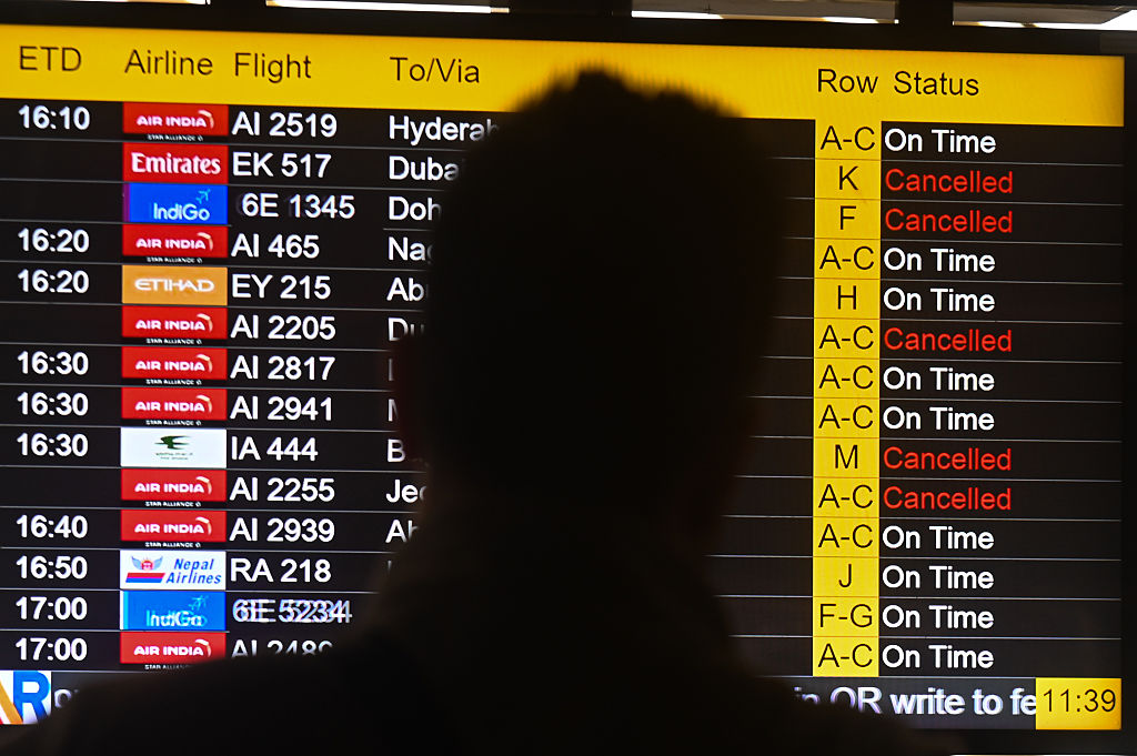 Passengers look at the screen displaying flight details as several flights are cancelled due to regional airspace closures. Kabir Jhangiani/NurPhoto via Getty Images