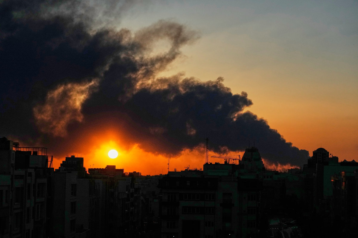 The sun sets behind a plume of smoke rising after a US–Israeli military strike in Tehran onMarch 3, 2026. (AP Photo/Vahid Salemi)