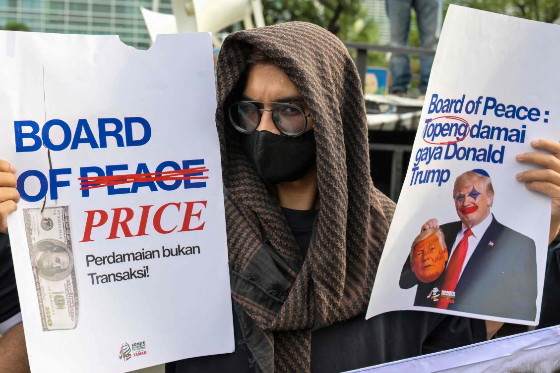 A protester holds placards that read "Board of Price: Peace is not a transaction" and "Board of Peace: peace mask Donald Trump-style" during a demonstration condemning US and Israeli attacks on Iran and Palestinians in front of the US Embassy in Jakarta on March 3, 2026. (AFP)