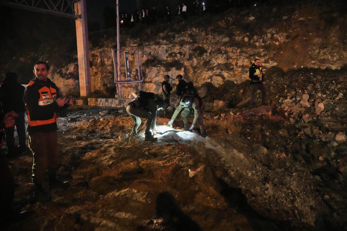 Israeli security forces inspect a damaged road after a missile launched from Iran struck Jerusalem, Sunday, March 1, 2026.(AP Photo/Mahmoud Illean)
