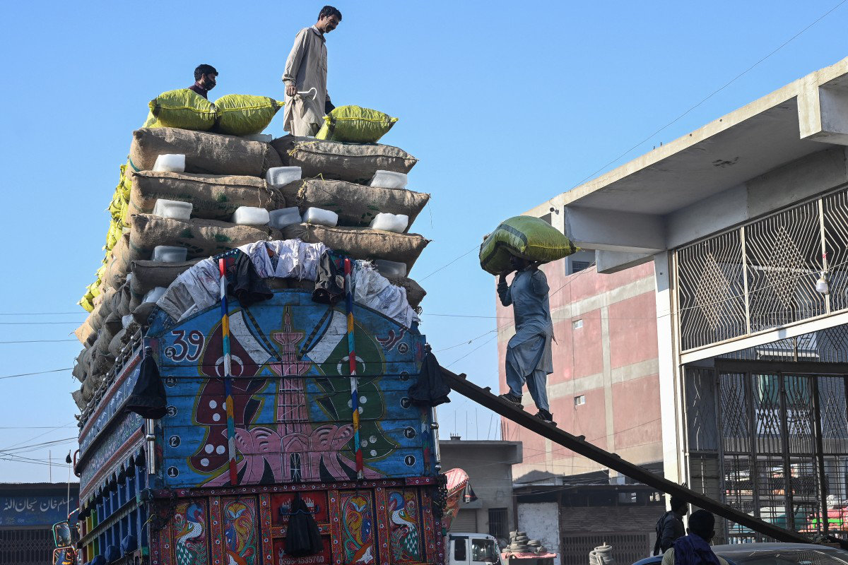 Pakistani workers load sacks of potatoes on a truck at a market in Karachi on February 14, 2026. (AFP)