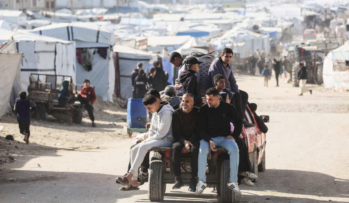 Palestinians ride in the back of a pick-up truck pas hundreds of tents are set up to house displaced Palestinians who lost their homes and businesses during Israeli military bombardment of the Gaza Strip, in Khan Yunis, in the south of the Gaza Strip on March 6, 2026. (AFP)