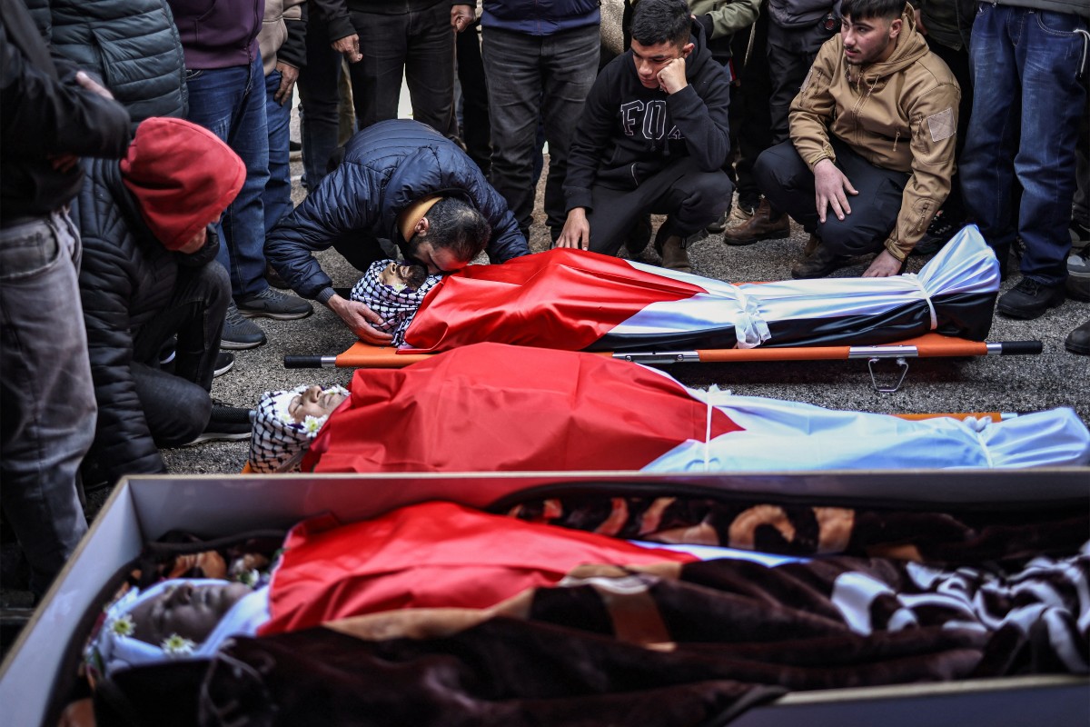 Mourners grieve by the bodies of three Palestinians killed in a reported attack by Israeli settlers in the town of Abu Falah, northeast of Ramallah in the occupied West Bank, during the funeral. (AFP)