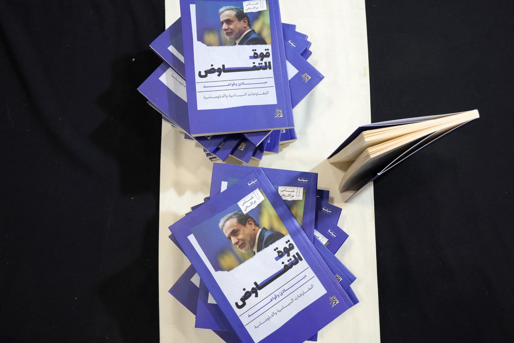 Copies of Iran’s Foreign Minister Abbas Araghchi’s book “The Power of Negotiation” are stacked on a table at the Muscat International Book Fair, April 25, 2025. (AFP)