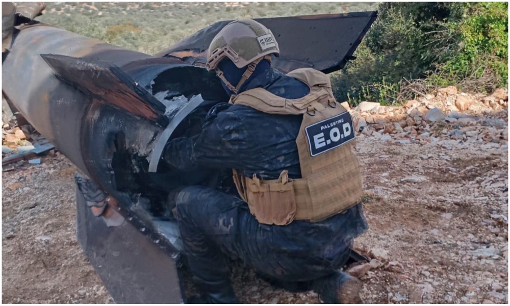 A Palestinian security officer handles a piece of an Iranian missile that fell in a town in the West Bank. (Wafa)