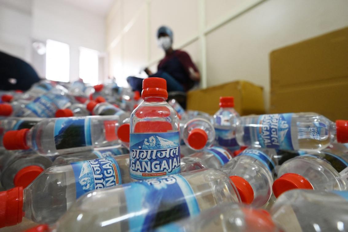Daily wage workers paste labels on the bottles with meltwater of Gangotri glacier which is the primary source of the pious river Ganges, at the Indian Post office in Uttarkashi. (FILE/AFP)