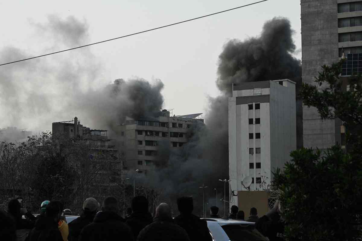 People watch a plume of smoke rising following an Israeli missile strike in the neighborhood of Bashoura in central Beirut on Thursday. (AFP)