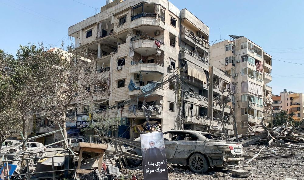 A banner bearing the image of Hezbollah leader Naim Qassem lies in front of damaged buildings following Israeli strikes, Beirut’s southern suburbs, Lebanon, Mar. 12, 2026. (Reuters)