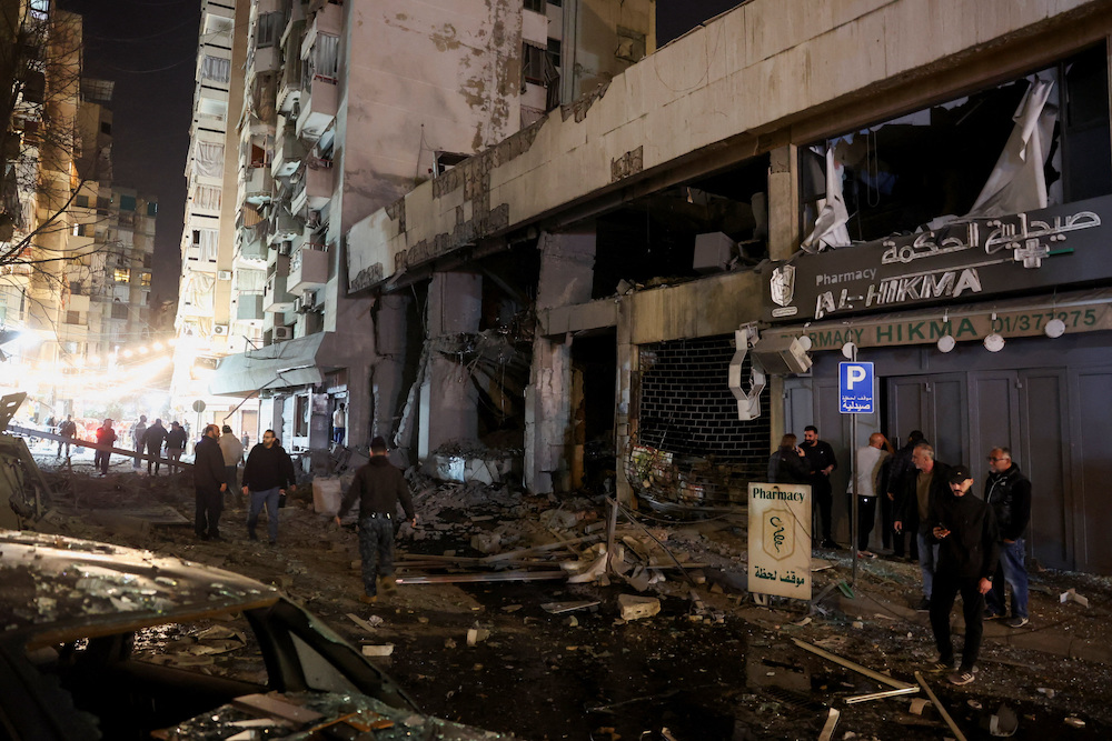 People stand amid debris in front of damaged buildings in the aftermath of a reported Israeli strike in Zuqaq al-Blat, central Beirut, following an escalation between Hezbollah and Israel amid the U.S.-Israeli conflict with Iran, Lebanon, March 12, 2026. (Reuters)