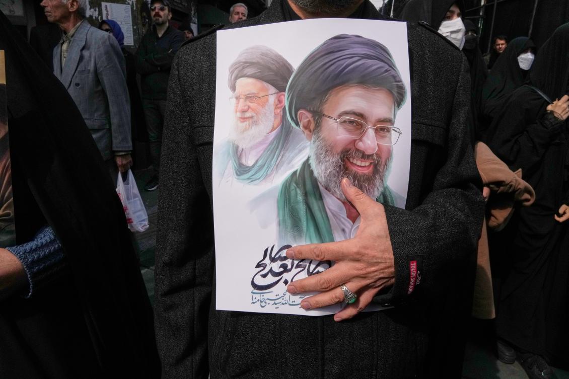 A mourner holds a poster depicting Ayatollah Mojtaba Khamenei, right, the successor to his late father Ayatollah Ali Khamenei. (AP)