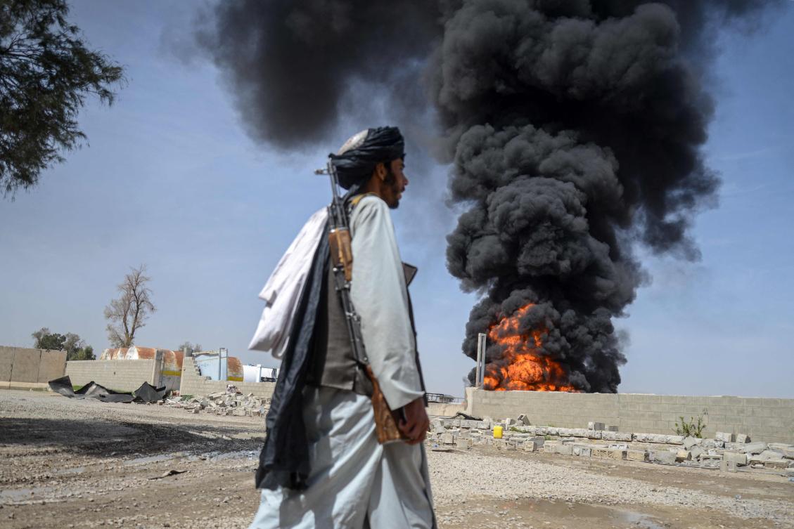 A Taliban security personnel walks as smoke rises from the site after overnight Pakistani airstrikes hit oil depots for commercial airlines, near the Kandahar airport in the Daman district of Kandahar province on March 13, 2026. Afghan authorities said on March 13 that Pakistan attacks on Kabul and border provinces killed four people in the capital and two in the east, the latest deadly clashes in the long-running conflict. (Photo by AFP)