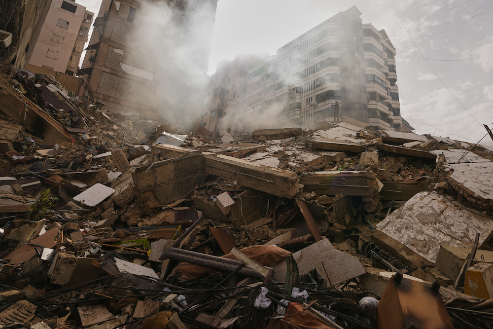 A man stands atop the rubble of a building destroyed in an Israeli airstrike as a bulldozer clears debris in Dahiyeh, Beirut's southern suburbs, Lebanon, Saturday, March 14, 2026. (AP)