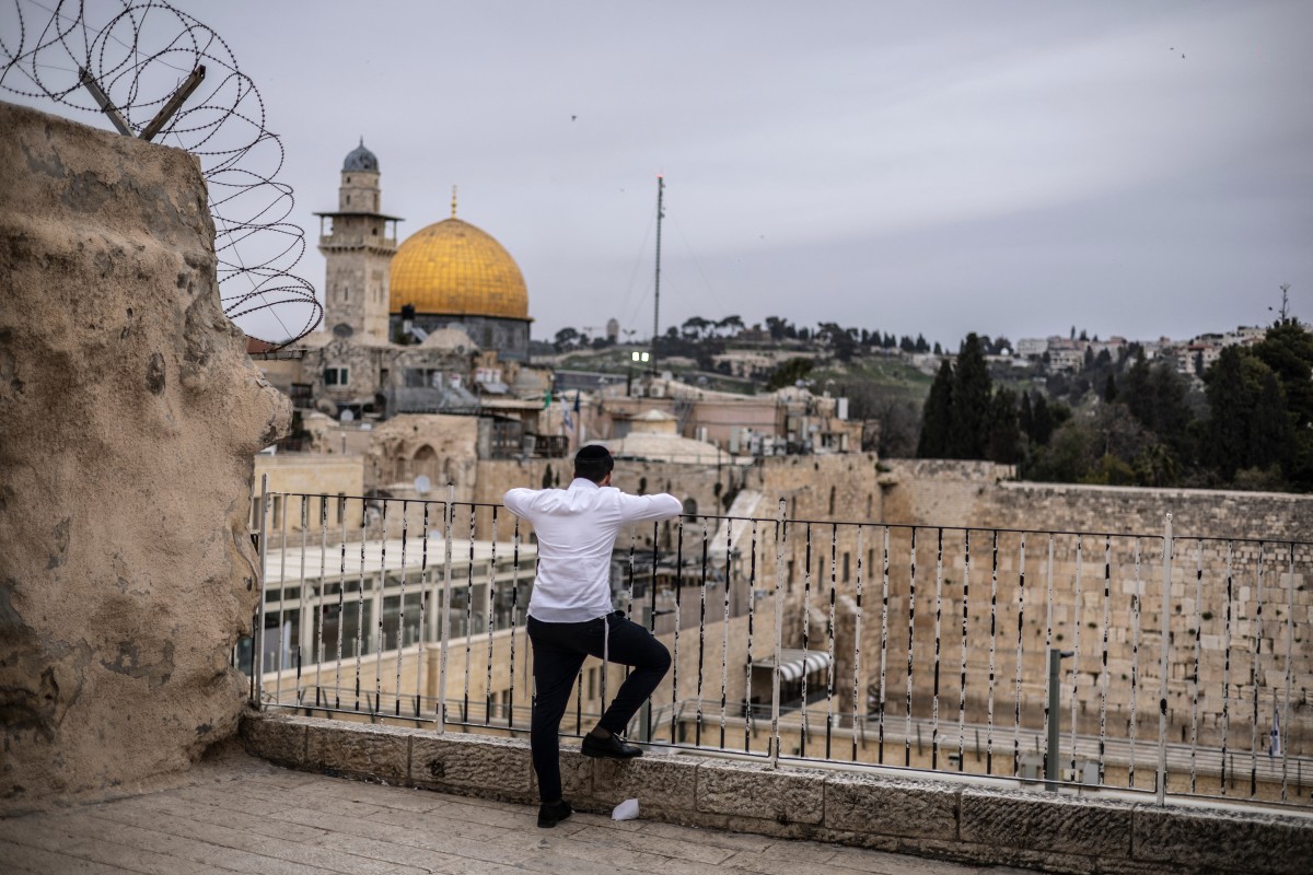 An ultra-Orthodox Jewish man prays in front of the closed Western Wall overlooking the Al-Aqsa compound and the Dome of the Rock in the Old city of Jerusalem, March 13, 2026. (AFP)