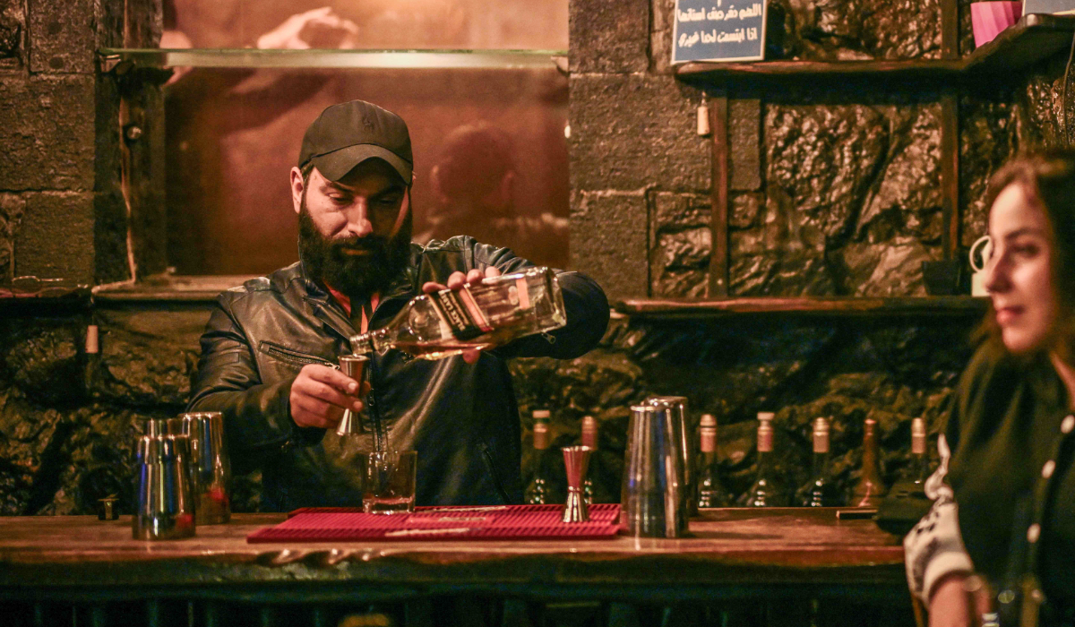 A pub owner serves whiskey to customers in Damascus on December 13, 2024. (AFP)