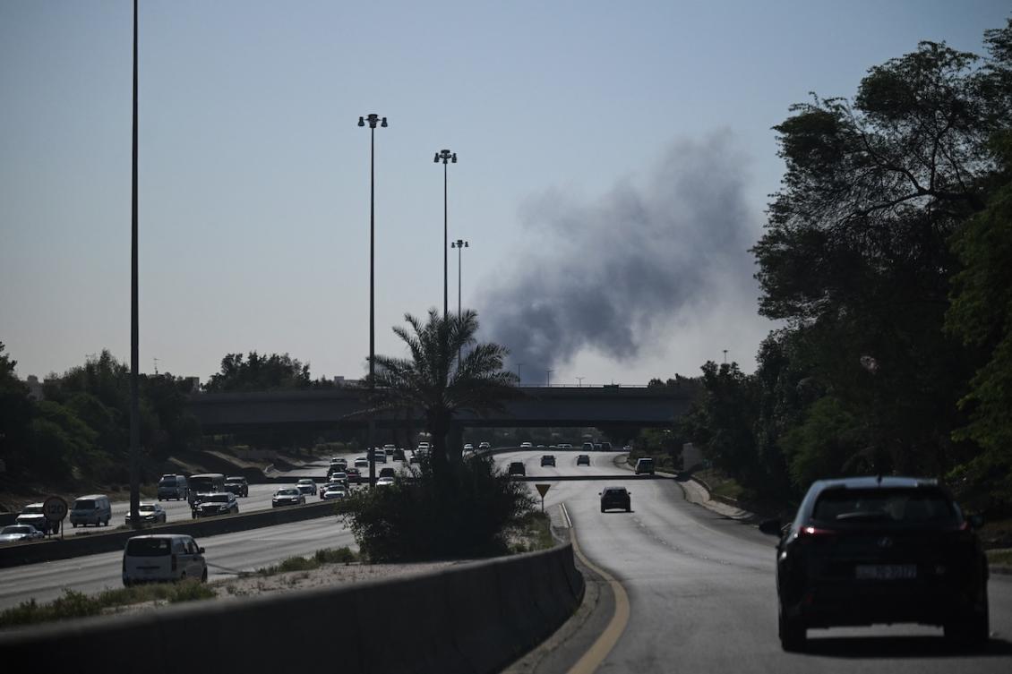 Motorists drive along a street as smoke rises from a reported Iranian strike in the area where the US Embassy is located in Kuwait City on March 2, 2026. (FILE/AFP)
