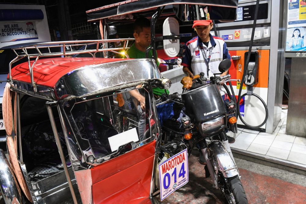 A petrol station employee fills up a tricycle with gasoline prior to a fuel price increase in Manila on March 17, 2026. (AFP)