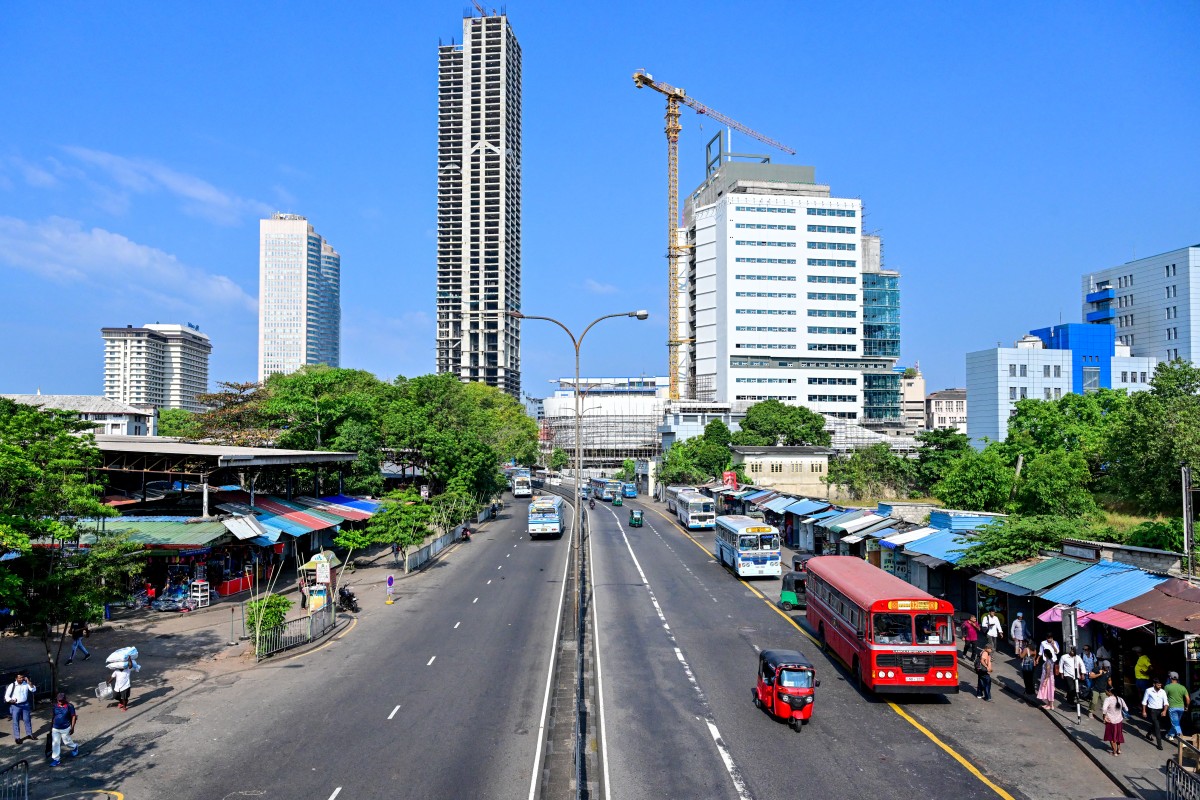 Sri Lankan commuters wait for public transport along a deserted road in Colombo on March 18, 2026. (AFP)