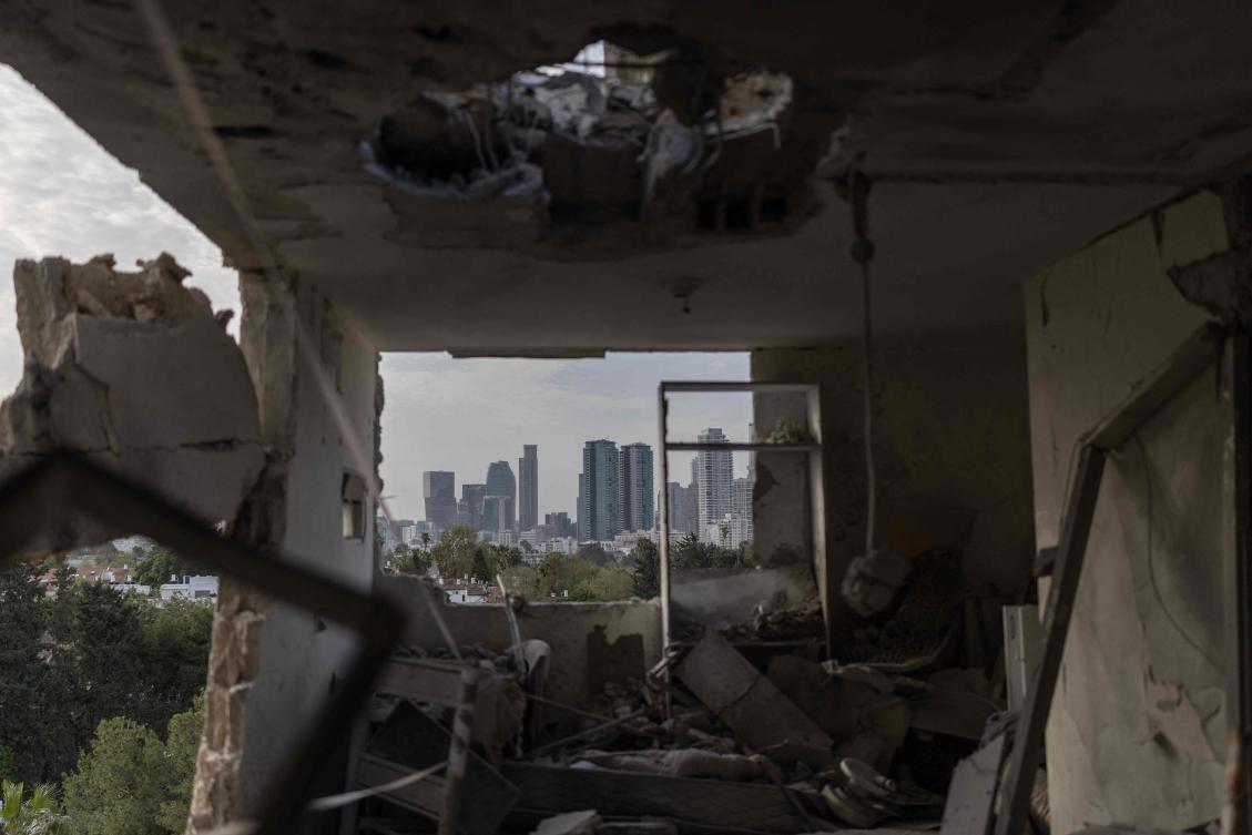 This photograph shows the interior of a destroyed apartment, with the Tel Aviv skyline visible in the background, following an overnight Iranian missile strike on March 19, 2026.(AFP)