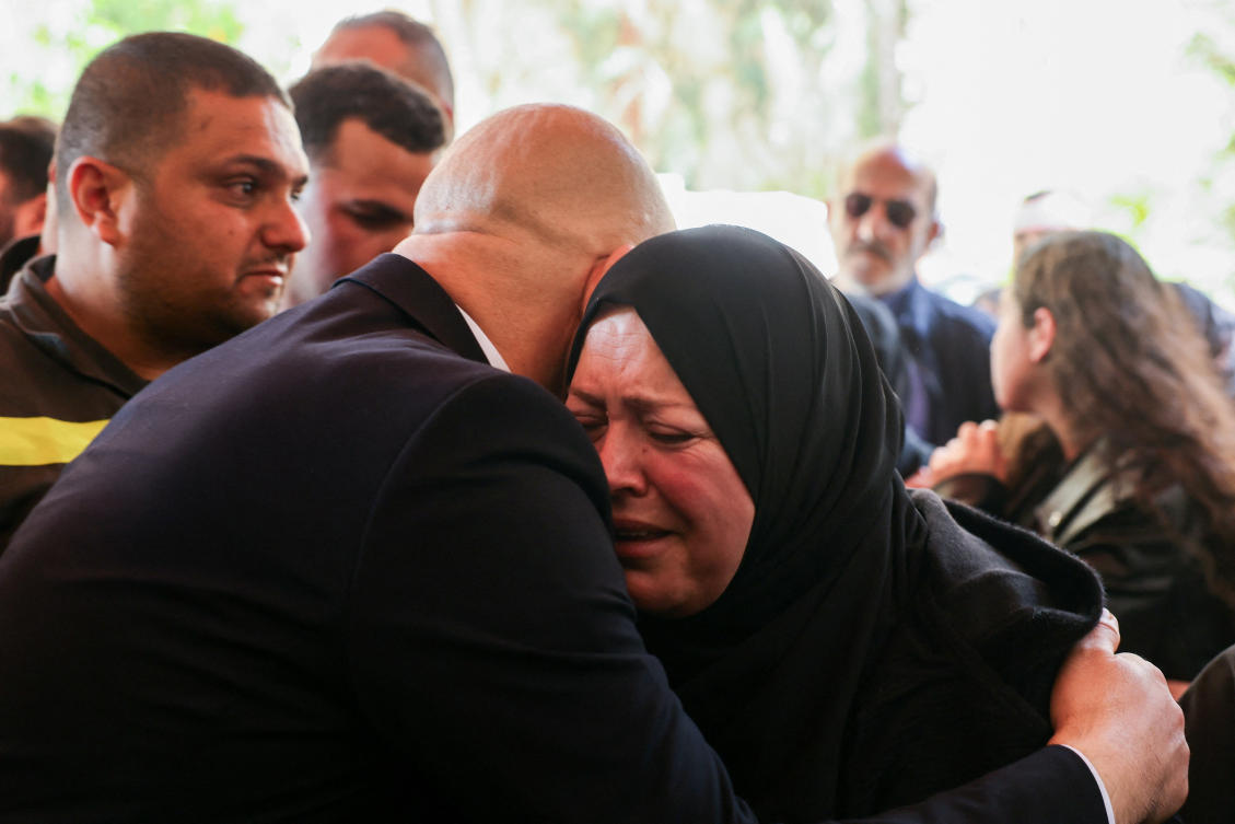 The wife of Fahmi Mahieddine Al-Chami, a member of the Lebanese Civil Defense who was killed on Wednesday in an Israeli airstrike targeting a vehicle in Sidon, is embraced during his funeral on Thursday. (Reuters)