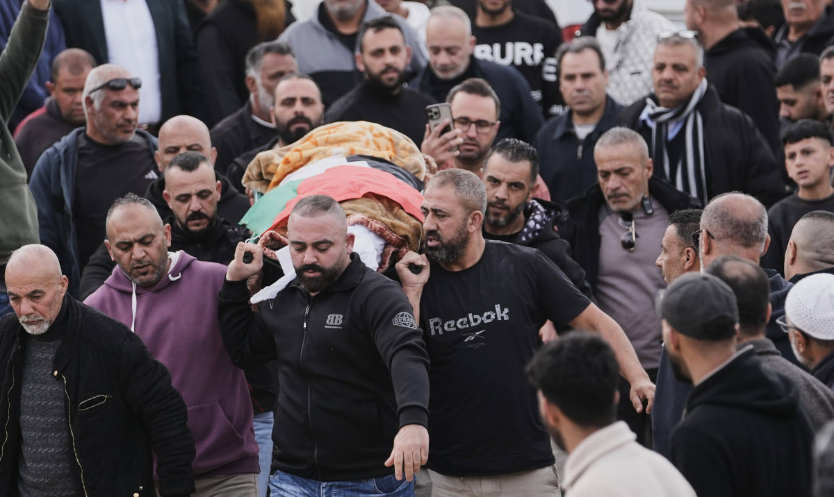 Palestinians carry the body of Palestinian woman who died after an Iranian strike, in the West Bank village of Beit Awa, near Hebron, Thursday, March 19, 2026. (AP)