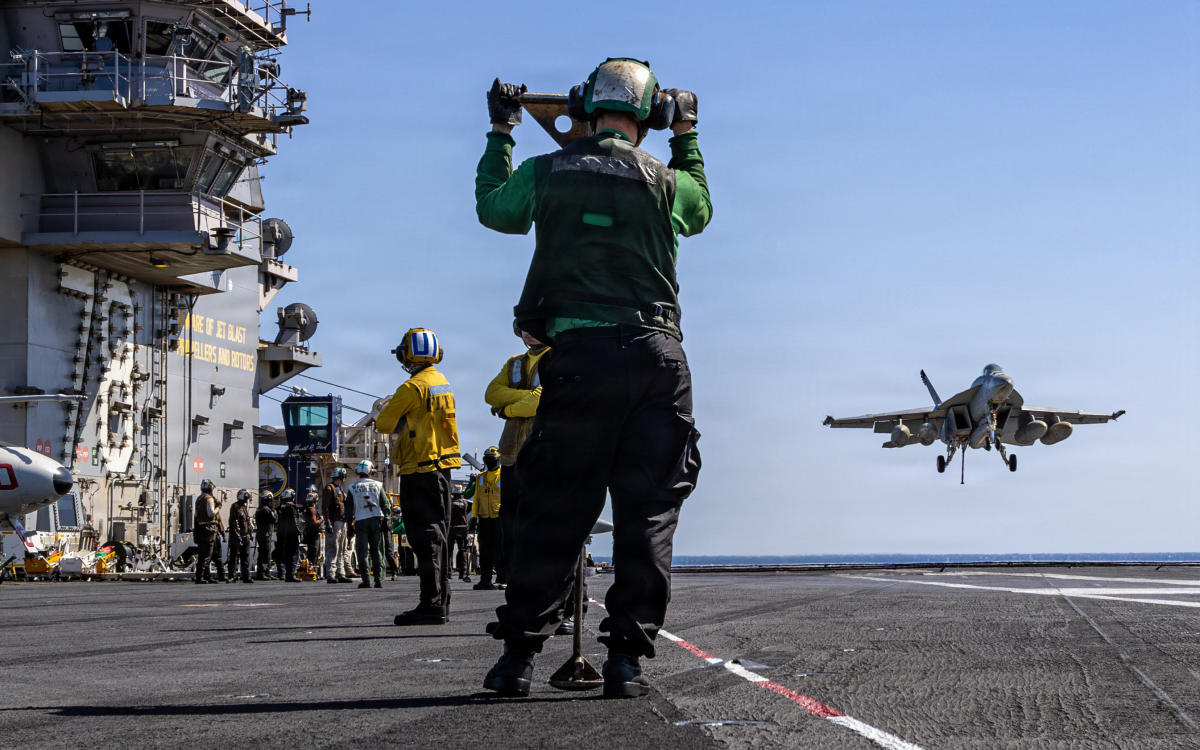 US sailors watch as an F/A-18E Super Hornet aircraft, assigned to Strike Fighter Squadron 31, approaches the flight deck of the world's largest aircraft carrier, USS Gerald R. Ford on March 8. (NAVCENT Public Affairs / DVIDS / AFP)