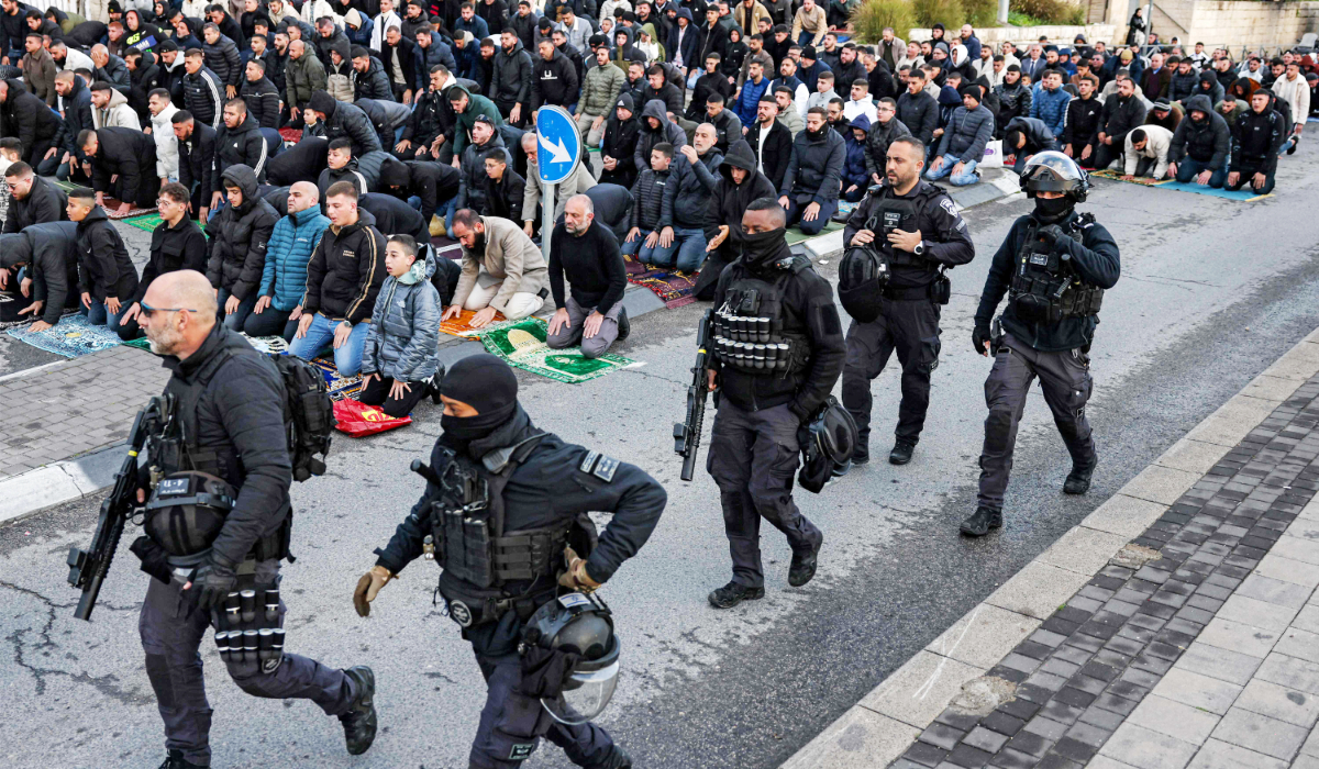 Israeli security forces walk past Muslim worshippers gathering outside the Jerusalem old city walls on March 20, 2026 to attend attend the early morning prayers for Eid al-Fitr, marking the end of the holy month of Ramadan. (AFP)