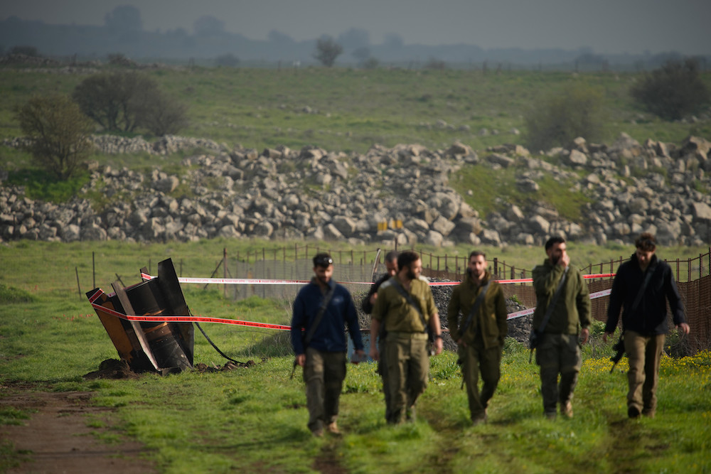 Israeli soldiers walk near a fragment of a missile fired from Iran, and intercepted by Israeli defense system, embedded in a open field in the Israeli-controlled Golan Heights, Thursday, March 19, 2026. (AP)