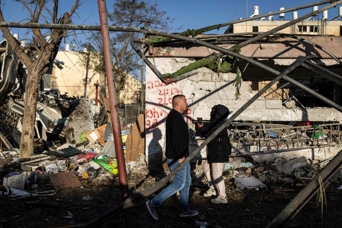 People walk through the site of an Iranian missile strike in Dimona, Israel. (AFP)