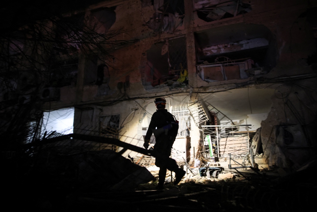 An Israeli emergency response official uses a torch to inspect the damage after Iranian missile barrages struck Dimona, Israel. (Reuters)